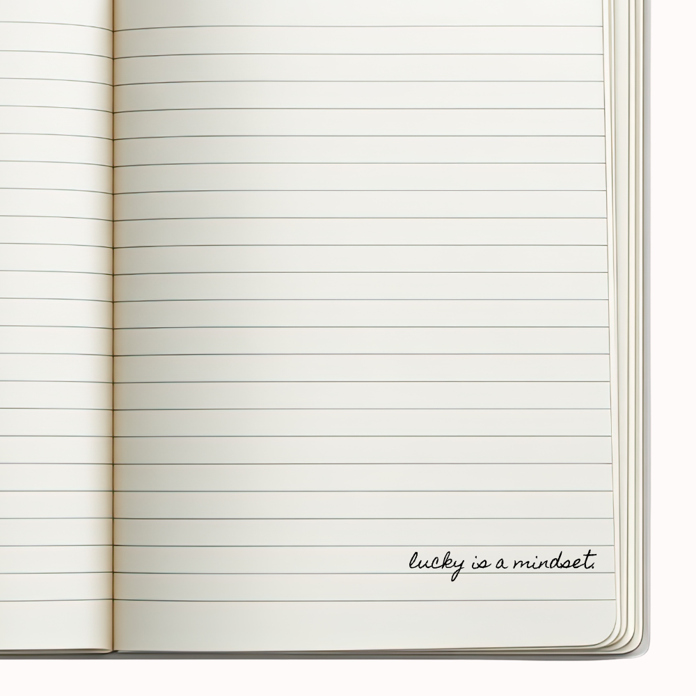 Open notebook with lined pages and 'lucky is a mindset' text on a white background