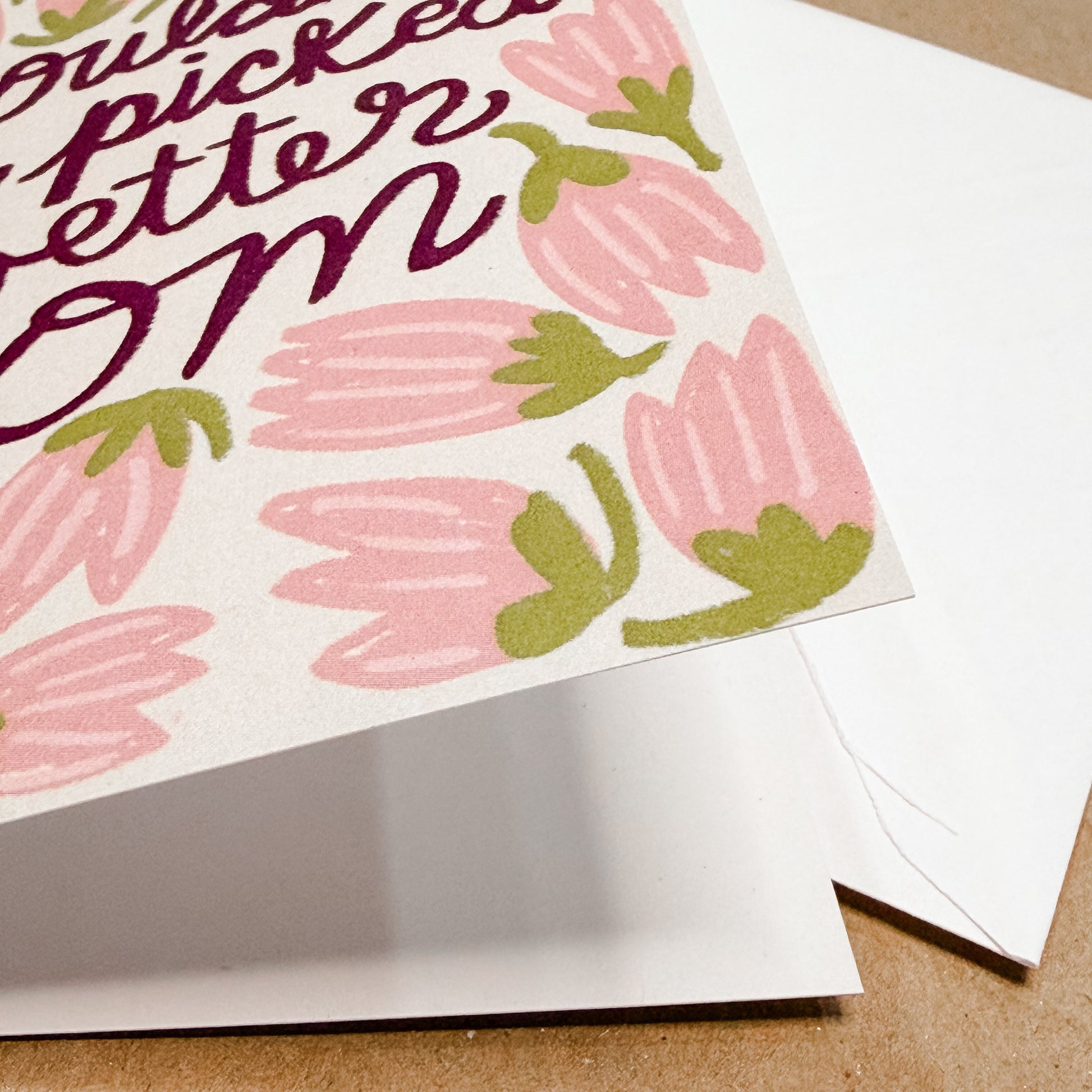 Greeting card with pink floral design and text on a brown surface