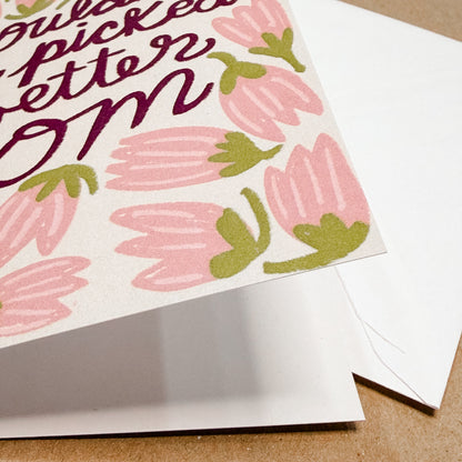 Greeting card with pink floral design and text on a brown surface