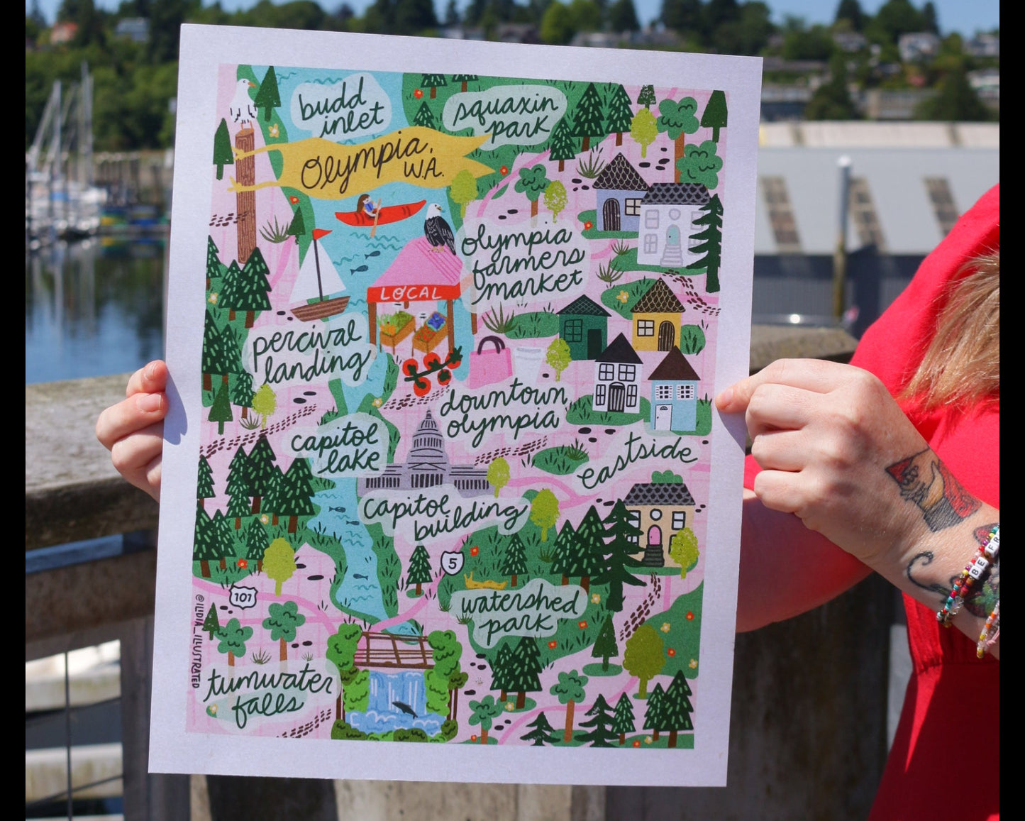 Person holding a colorful map of a town with a clear blue sky in the background.