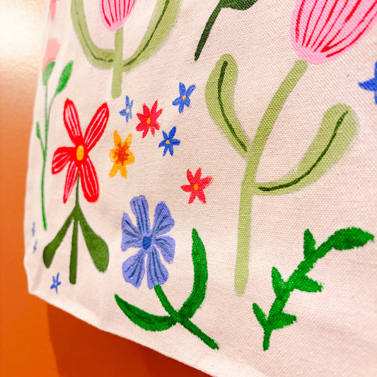 Hand painted tote with colorful floral motifs on a plain background