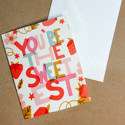 Greeting card with 'You're the Sweetest' text and a white envelope on a brown background