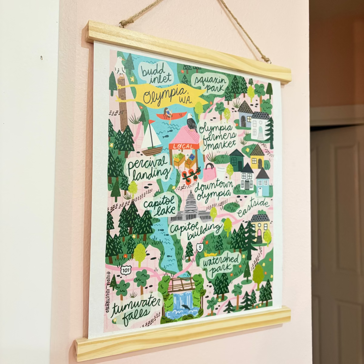 Colorful illustrated map of Olympia hanging on a wall with a wooden frame.