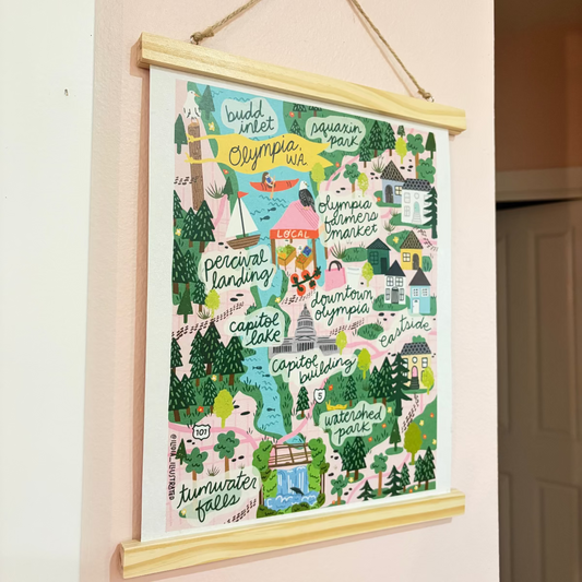 Colorful illustrated map of Olympia hanging on a wall with a wooden frame.