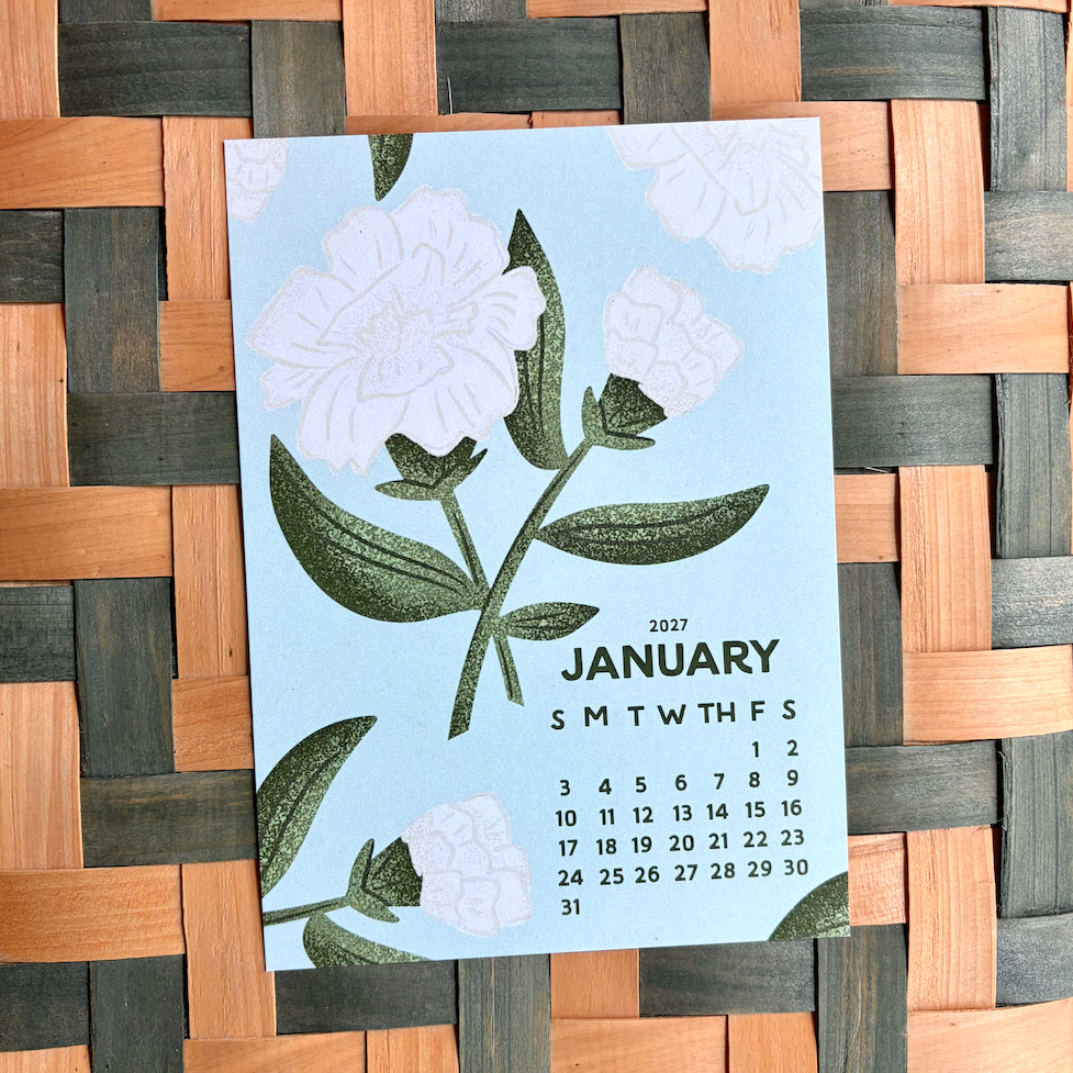 January calendar card with floral design on a woven mat background