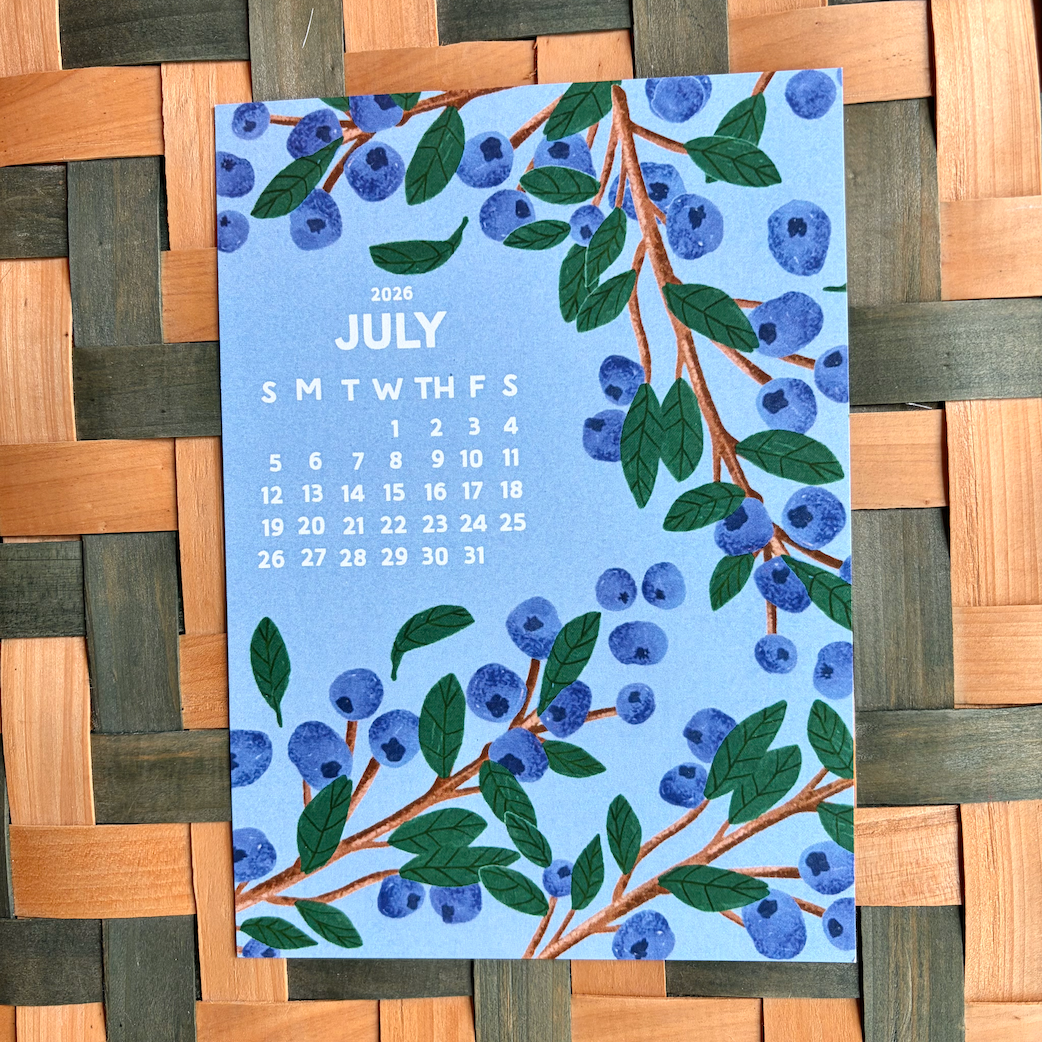 July 2026 calendar card with blueberry design on a woven surface