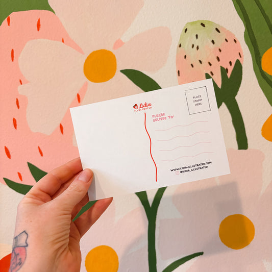 Hand holding a Olympia MAP postcard with floral design in the background