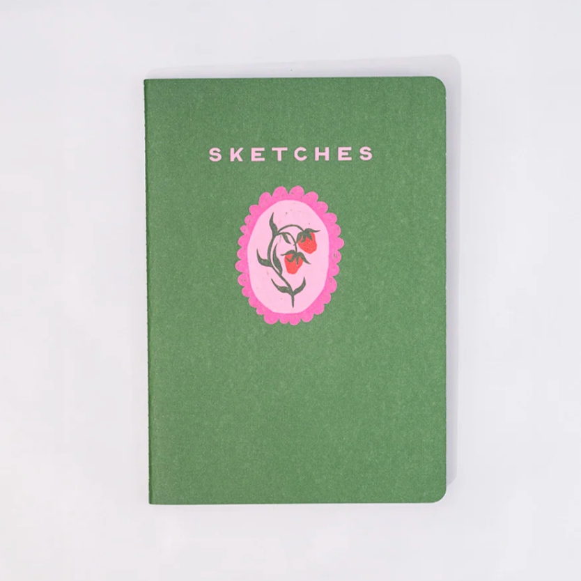 Green notebook with a pink floral emblem and 'Sketches' text on a white background