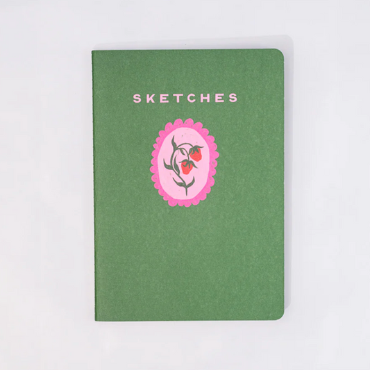Green notebook with a pink floral emblem and 'Sketches' text on a white background