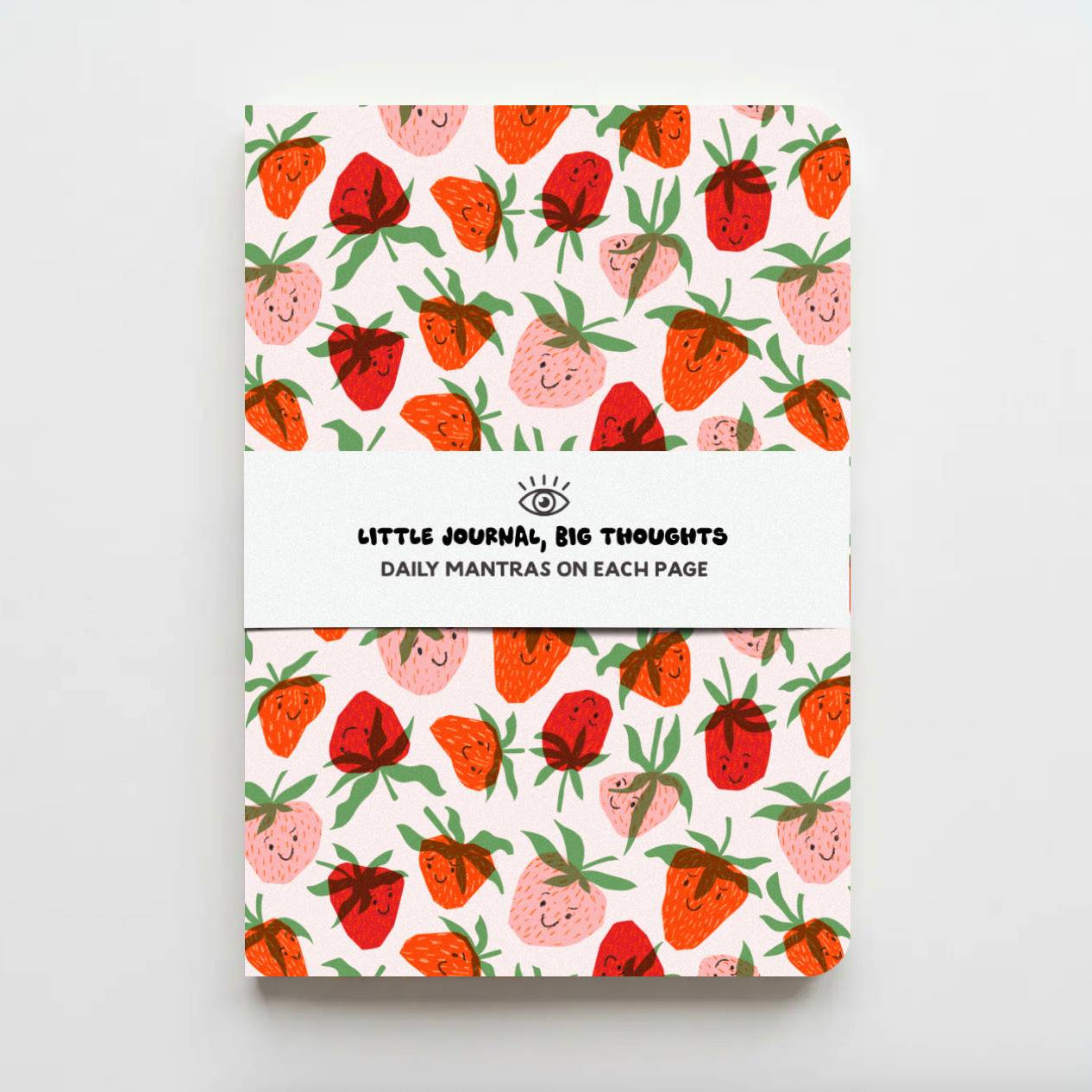 A notebook with a white cover featuring a repeating pattern of cute, smiling strawberries in red, pink, and orange with green leaves. A white paper band wrapped around the center reads 'LITTLE JOURNAL, BIG THOUGHTS' and 'DAILY MANTRAS ON EACH PAGE'.