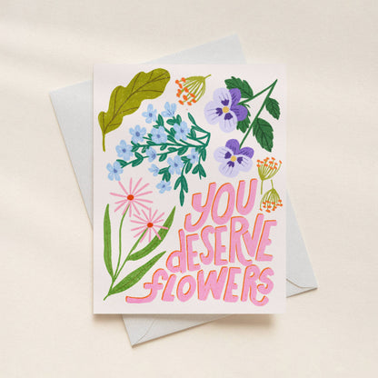 Greeting card with floral design and 'You Deserve Flowers' text on a beige background