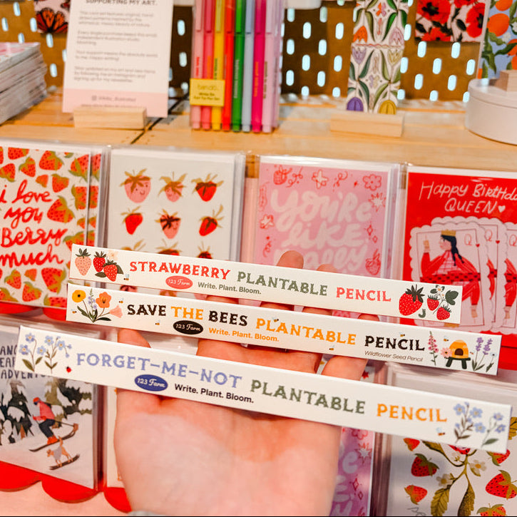 Display of plantable pencils and greeting cards with a decorative background.