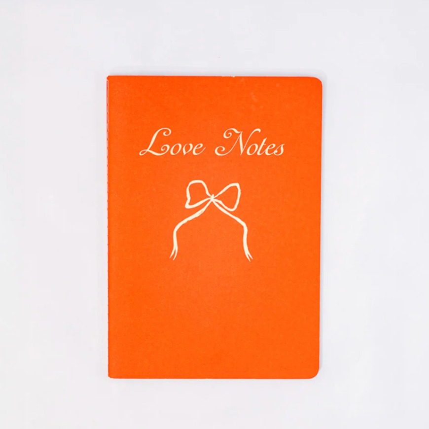 Orange notebook with 'Love Notes' and a bow illustration on a white background