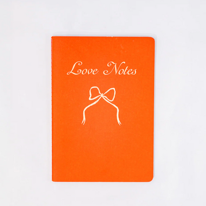 Orange notebook with 'Love Notes' and a bow illustration on a white background
