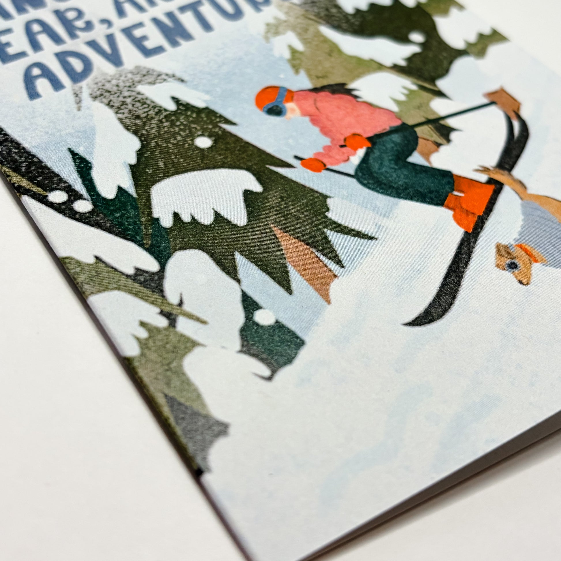 Card with illustration of a person skiing through a snowy landscape and text 'Another Year, Another Adventure'.